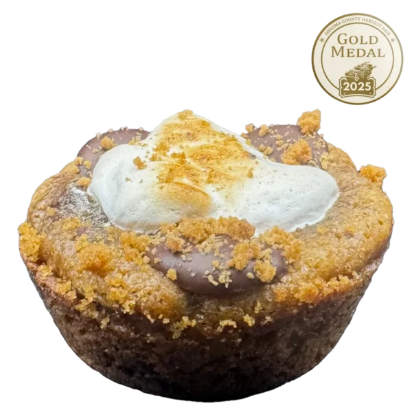 Gourmet S'mores cookie with a thick dough base, melted chocolate, graham cracker pieces, whipped peanut butter, and toasted honey marshmallow fluff, topped with mini peanut butter cups and salt flakes.