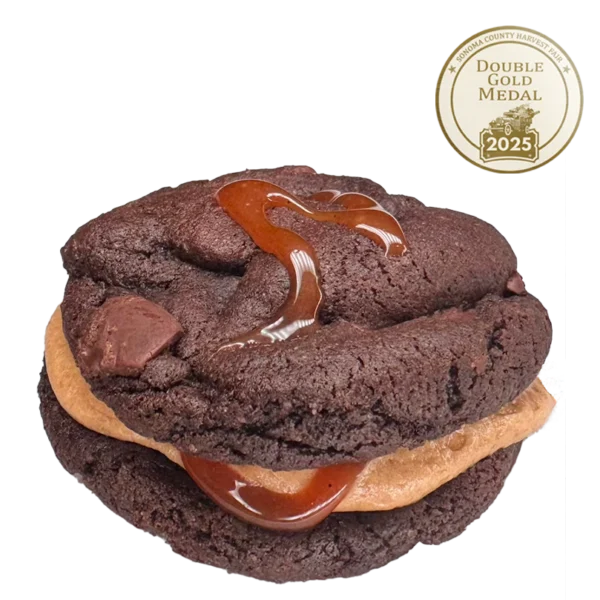 Chocolate Cookie Sandwich featuring chocolate chunks, filled with whiskey buttercream and drizzled with salted caramel.