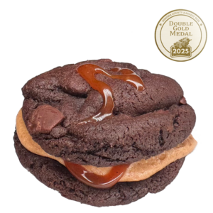 Chocolate Cookie Sandwich featuring chocolate chunks, filled with whiskey buttercream and drizzled with salted caramel.