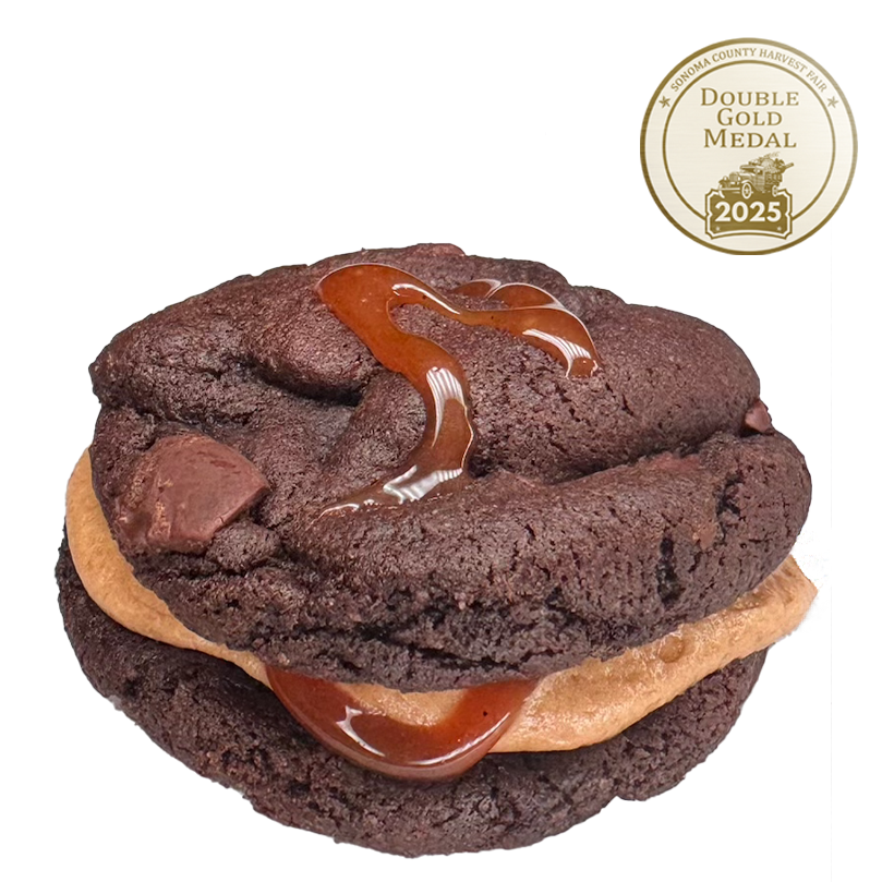 Chocolate Cookie Sandwich featuring chocolate chunks, filled with whiskey buttercream and drizzled with salted caramel.